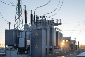 Power transformer at the substation with the rays of the morning sun. Energy. Cold winter dawn at...