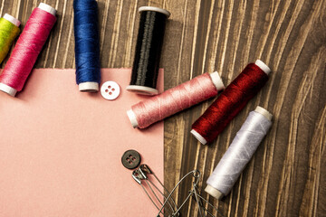 Sewing still life with sewing threads and sewing related objects on wooden background