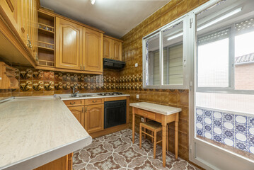 Kitchen furnished with Castilian-style wooden furniture, folding table on one side and striking...