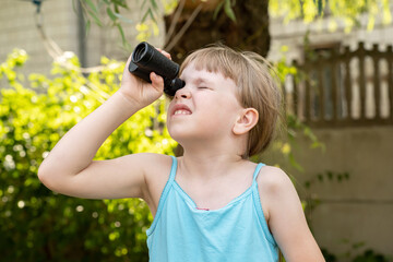 Elementary school age girl looking up into the sky through a magnifying monocular watching birds,...
