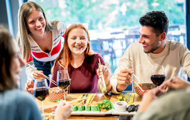 Young trendy friends eating with chopsticks at sushi bar restaurant - Food and beverage concept...