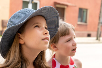 Two elementary school age girls Caucasian European kids outdoors, summer portrait, face closeup, sun hat, children on vacation holidays real people lifestyle. Sisters, siblings, close friends together