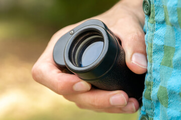 Man holding a simple magnifying monocular glass, modern spy spyglass in hand, object detail, closeup. Spying on someone, stalking, searching, looking for something, bird watching abstract concept