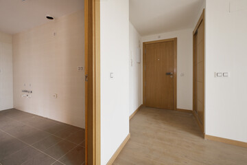 Entrance hall of an empty house with an oak wood access door to match the rest of the doors, a built-in wardrobe with sliding doors and stoneware floors and laminated flooring