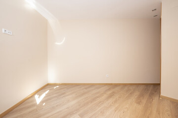Empty living room of a house with floating wood flooring with cream colored walls