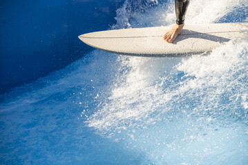 A surfer enjoying the crests of the waves in an urban wave pool in his black wetsuit - Powered by Adobe