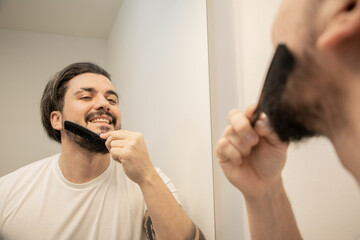 Handsome young man combing his beard