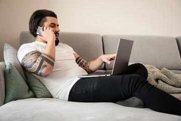 Handsome young man on the phone in front of laptop