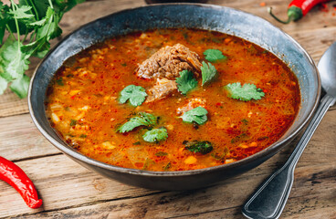 Traditional Georgian tomato soup Kharcho with beef and rice on rustic wooden background.