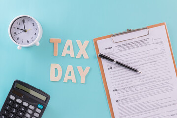 Tax fill concept - 'Tax day' word, clock, pen and calculator  with W-8-BEN form on blue or green backgound color