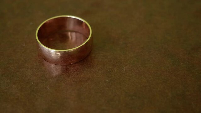 One golden wedding ring on brown background, closeup