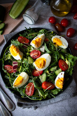 Salad with egg, arugula, tomatoes. On a concrete background. Vegetarian