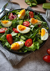 Salad with egg, arugula, tomatoes. On a concrete background. Vegetarian