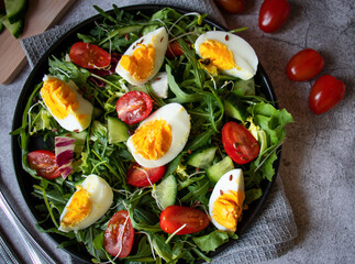 Salad with egg, arugula, tomatoes. On a concrete background. Vegetarian