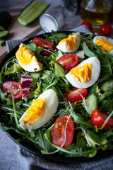 Salad with egg, arugula, tomatoes. On a concrete background. Vegetarian