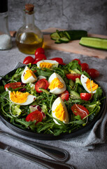 Salad with egg, arugula, tomatoes. On a concrete background. Vegetarian