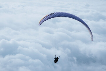 Paragliding in the sky. Paraglider flying above the clouds. Two men paraglide