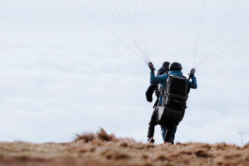 Two men take off their paragliding flight. Two men start paragliding
