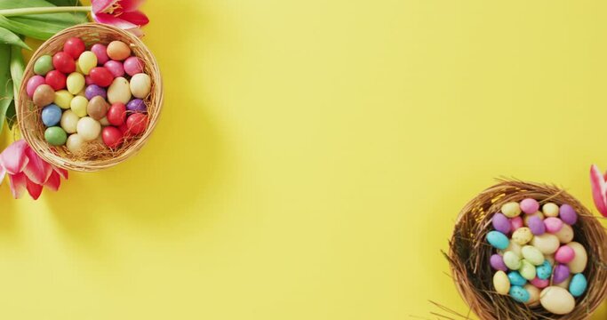 Video of decorated colorful easter eggs and flowers on a yellow surface
