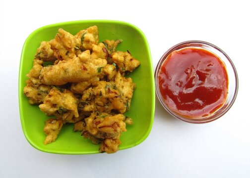 Besan pakora in a bowl with tomato ketchup  on white background 