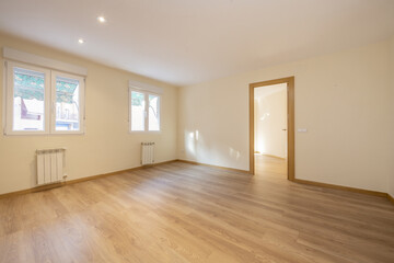 Empty room with wooden flooring, aluminum windows with radiators below with green awnings on the outside and oak joinery