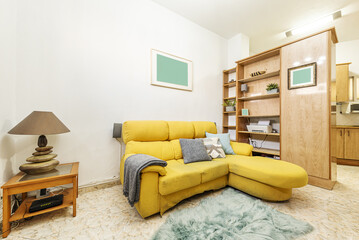 Living room of a rental house decorated with wooden furniture with a yellow chaise longue sofa and...