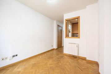 Empty room of an apartment with oak parquet laid in a herringbone pattern, window with hatch and oak joinery and electric radiator under the window