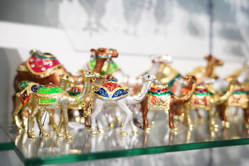 Small colourful metal camels on a glass shelf for display and buying at the souvenir or gift shop....