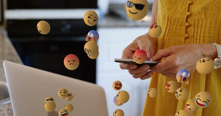 Animation of emoticons floating over hands of caucasian woman using smartphone - Powered by Adobe