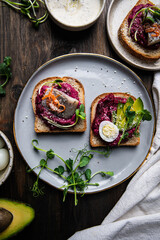 Three smorrebrods (open sandwiches) with toppings: herring, beetroot paste, quail eggs, avocado and...