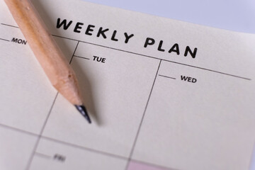 Weekly planner and wooden pencil. Calendar reminder, organizer, schedule, planning concept. Close-up of weekly plan paper