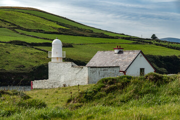 Fototapeta na wymiar The bright white Dingle lighthouse surrounded by lush green meadows, Dingle Peninsula, County Kerry, Ireland