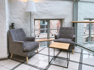 Modern interior design. Two gray armchairs, metal wrought-iron table, floor lamp. Large windows on...
