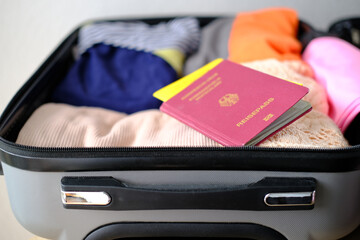 close-up of bright women's passport, covid certificate, things, folded clothes in open silvery...