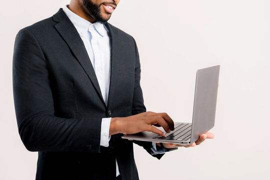 Cropped photo of bearded african-american freelancer guy using laptop computer isolated on white background, dark-haired 30s multiracial man in formal black suit typing, face is not visible
