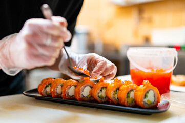 professional chef's hands making sushi and rolls in a restaurant kitchen