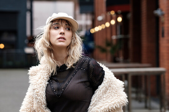 Pensive young woman is posing in an urban environment.