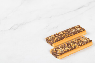 Two Crispy cookies in the form of strips glazed with chocolate, with nuts and cereals. White background. Copy space