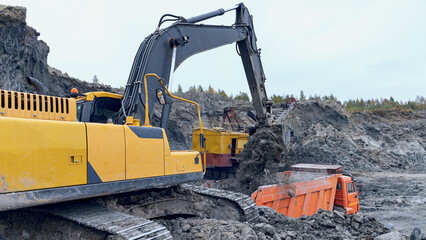 modern excavator loading soil into truck at construction site - 577158615