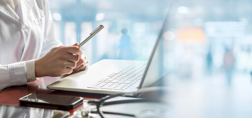 Doctor with a pen in his hands sits at a computer .