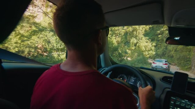 Man steers the car along the narrow road in mountains