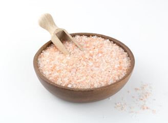 Crystalline pink salt in a wooden bowl on a white background. Himalayan pink salt. Top view.