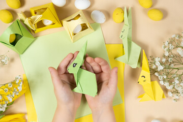 Handicrafts from paper for Easter - origami, making figurines of Easter bunnies, child hands...