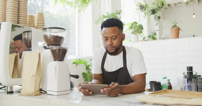 African american male cafe owner standing by counter using tablet at cafe