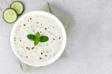 Indian raita sauce with yogurt, cucumber and mint on a gray background. Top view. Indian food. Greek tzatziki sauce.