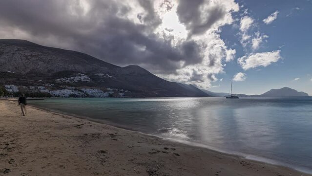 Panorama showing Amorgos island aerial timelapse from above with clouds on a blue sky. Traditional Greece - beach with hills and turquoise sea, Cyclades