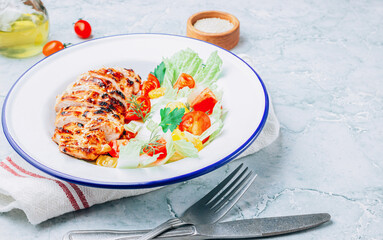 Fried chicken fillet and fresh vegetable salad of tomatoes over gray marble table. Grilled chicken breast. Healthy food.