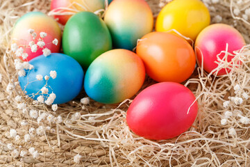 Fototapeta na wymiar Easter painted colorful natural chicken eggs with dried hay and flowers lying on rustic background.