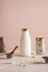 seed milk in bottle on beige background with chia, flax, sunflower, sesame seed. Raw diet meal. Healthy vegetarian food and lifestyle. eco friendly