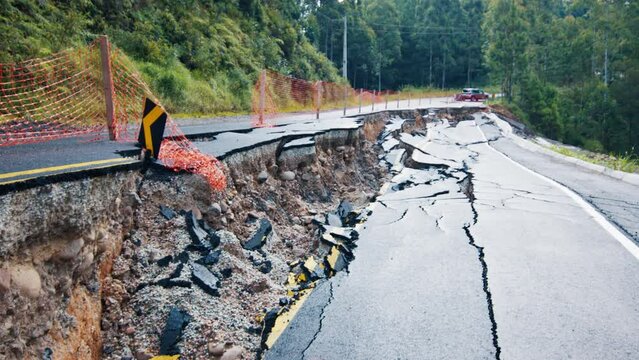Damaged asphalt road in the mountains. Mudflow aftermath, cracked paved road